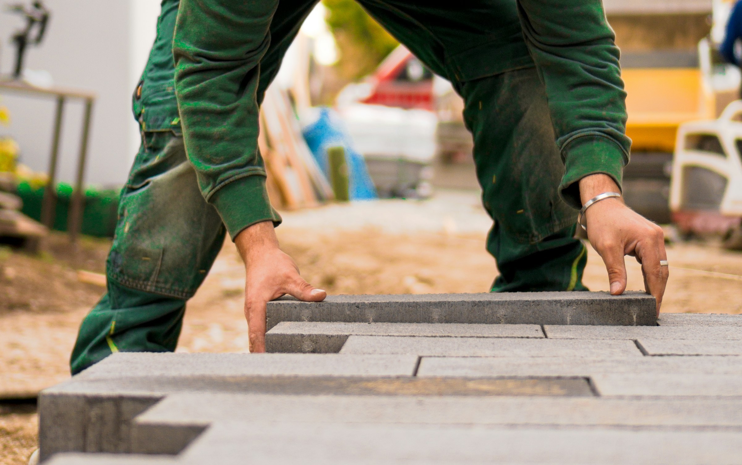 Hands setting a paver into place on a prepared base