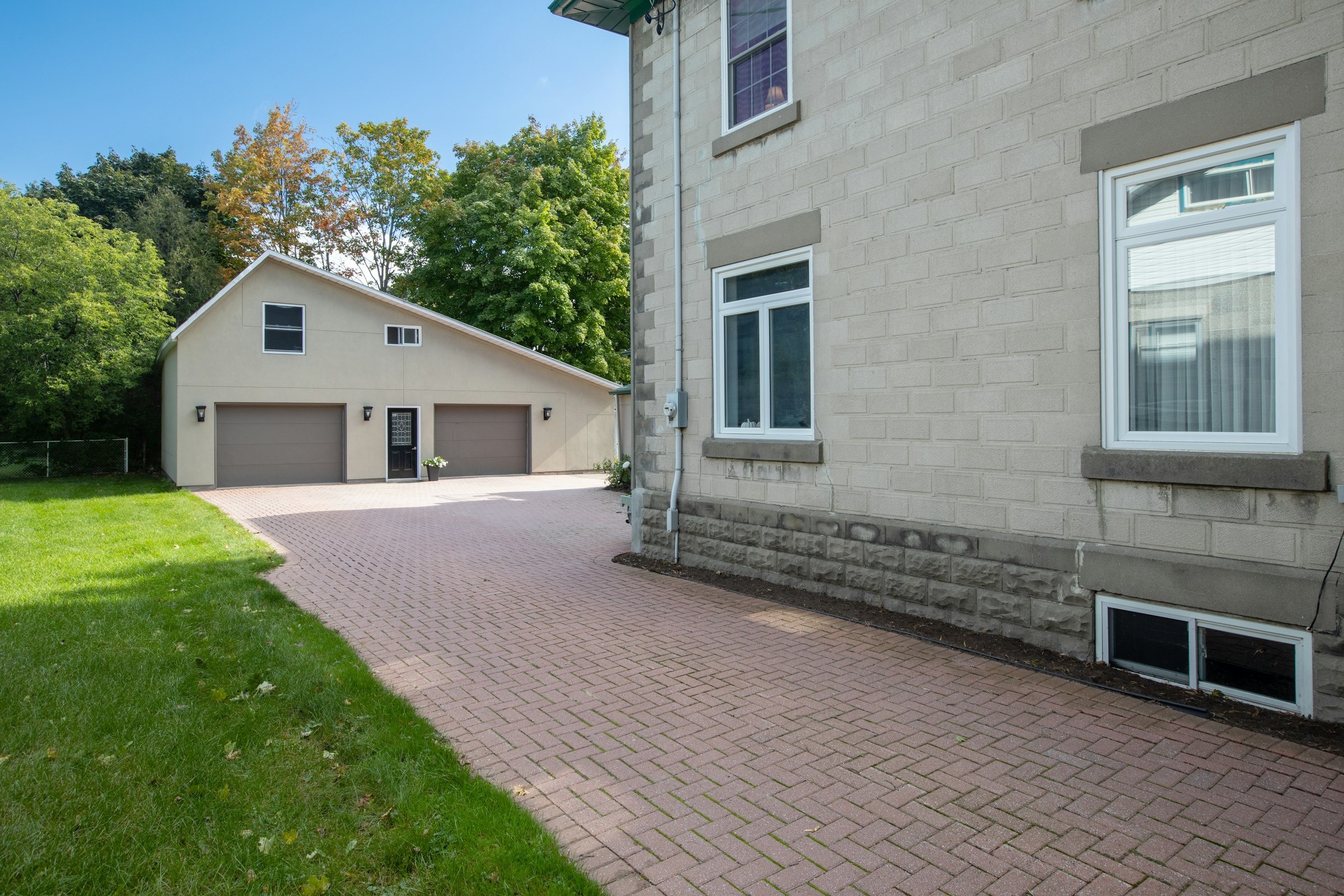 Herringbone brick paver driveway leading to a two car garage