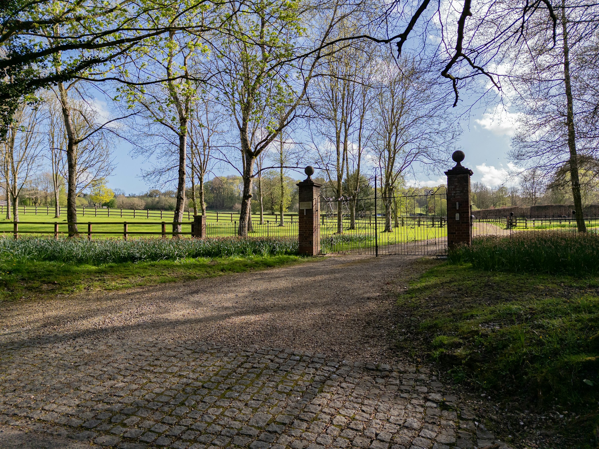Cobblestone estate driveway leading to brick gate pillars