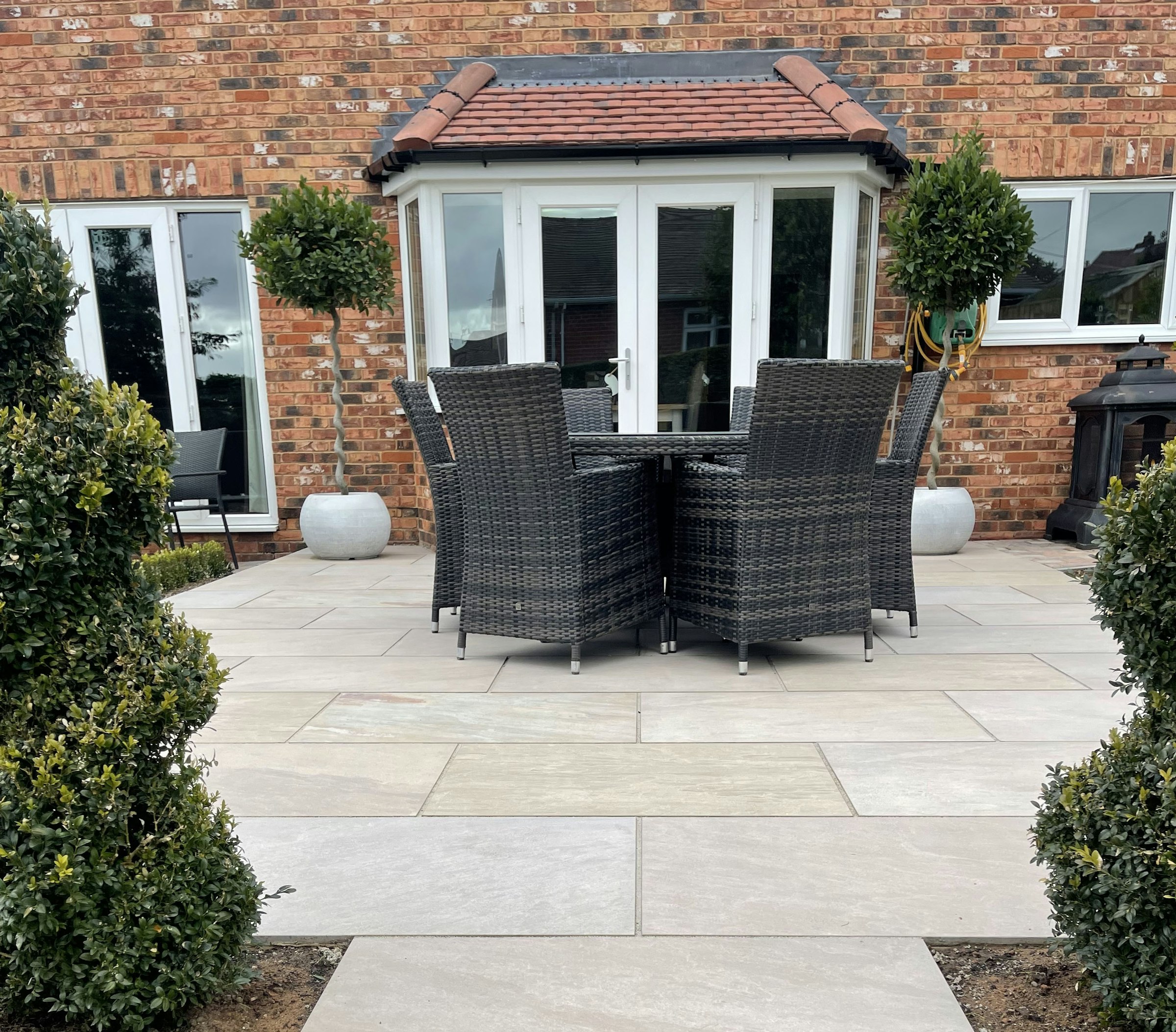 Light stone paver patio with outdoor dining set beside a brick house