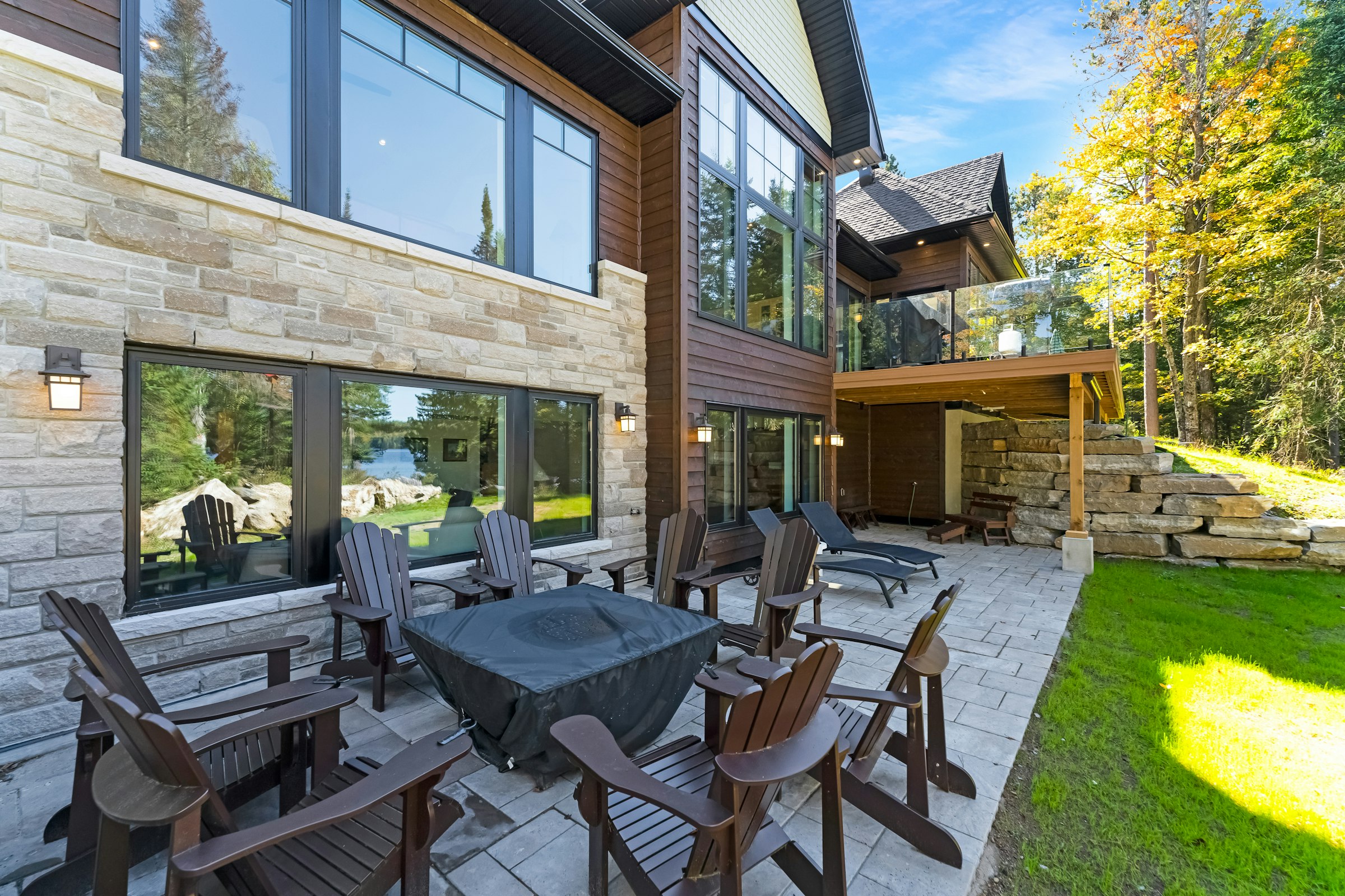 Paver patio with outdoor seating beside a stone-faced house and stacked stone wall
